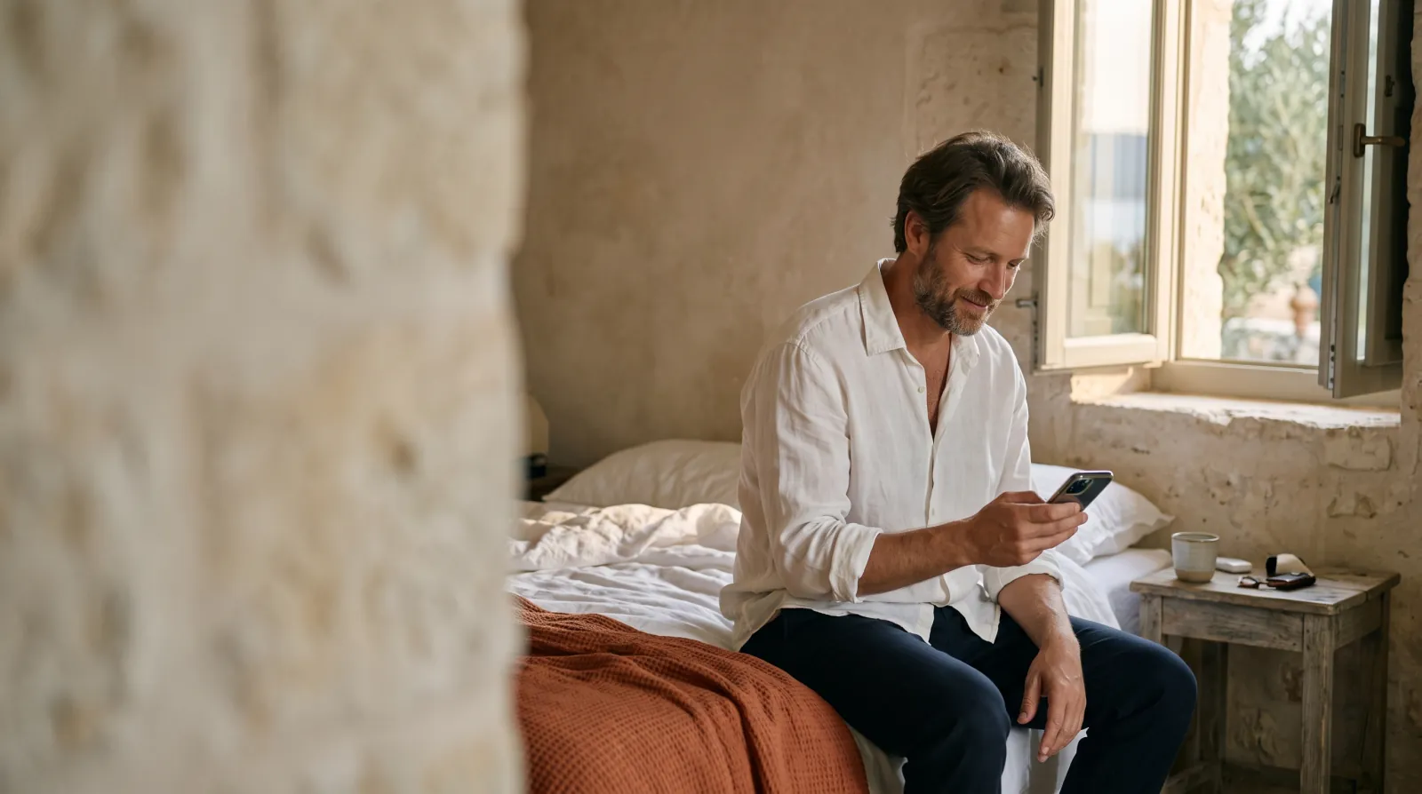 A guest sitting on a hotel bed writing a message on a phone